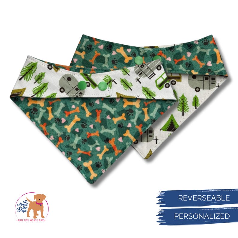 Op de afbeelding: Twee omkeerbare hondenbandana's. De ene kant heeft een groene achtergrond met oranje en gele botten en pootafdrukken. De andere kant heeft een witte achtergrond met groene bomen en een kampeerwagen. Groene knopen bevestigen de bandana.