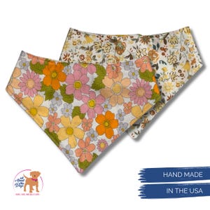 Pode incluir: Duas bandanas florais para c&atilde;es. Uma apresenta flores laranja, rosa e amarelas sobre um fundo branco. A outra tem um fundo creme com flores castanhas e amarelas. O texto diz "HAND MADE IN THE USA."