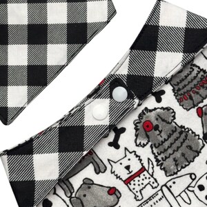 Pode incluir: Bandana para c&atilde;es com um padr&atilde;o xadrez preto e branco e um tecido branco com ilustra&ccedil;&otilde;es de c&atilde;es. A bandana tem dois fechos de press&atilde;o brancos.