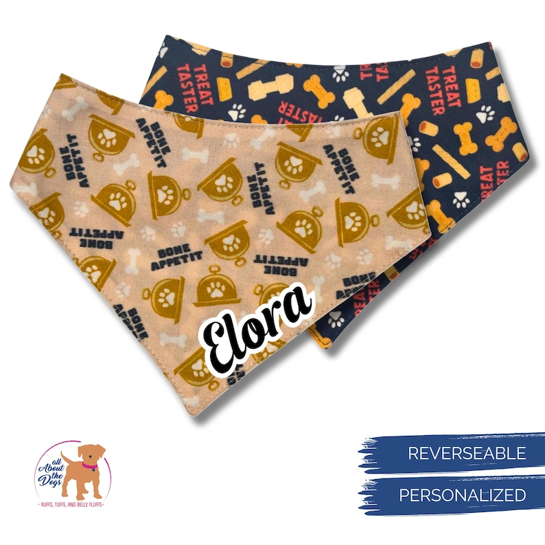 May include: Two reversible dog bandanas. One is tan with paw prints, dog bowls, and the text "Bone Appetit". The other is navy blue with bones and the text "Treat Taster". One bandana is personalized with the name "Elora".