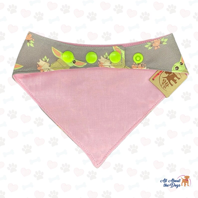 Puede incluir: Un pa&ntilde;uelo reversible para perro rosa y gris con un estampado de personaje extraterrestre verde. El pa&ntilde;uelo tiene cuatro botones a presi&oacute;n verdes y una etiqueta marr&oacute;n que dice "All About the Dogs".