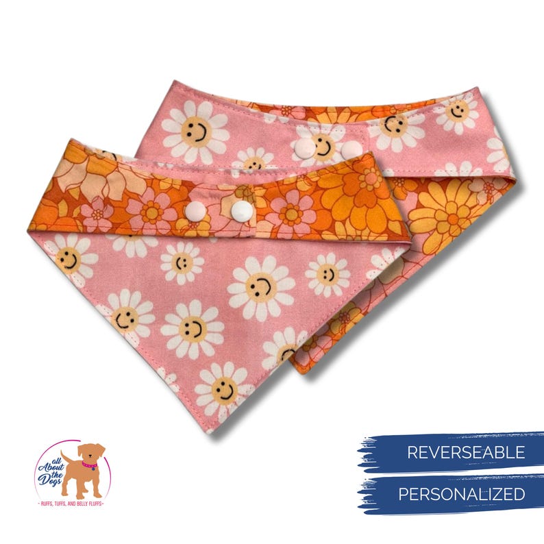 Puede incluir: Dos pa&ntilde;uelos reversibles para perros. Uno es rosa con caras de margaritas blancas, el otro es floral naranja y amarillo. Ambos pa&ntilde;uelos tienen cierres de bot&oacute;n a presi&oacute;n blancos. Los pa&ntilde;uelos son personalizados.