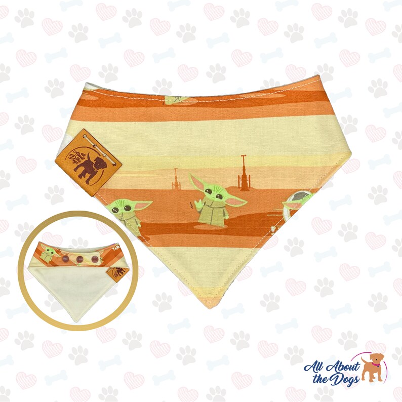 May include: Dog bandana featuring a design with Baby Yoda and a desert landscape in orange and yellow stripes. Includes a small, attached tag with the text "All About the Dogs".