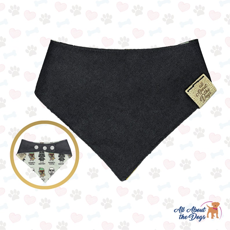 May include: Black dog bandana with a Star Wars theme featuring characters like Darth Vader, Yoda, and Chewbacca. The bandana has a snap closure and is reversible. The bandana is on a white background with hearts and bones.