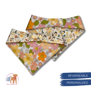 Pode incluir: Duas bandanas revers&iacute;veis para c&atilde;es com um padr&atilde;o floral em tons de amarelo, laranja, rosa e verde. As bandanas t&ecirc;m fecho de bot&atilde;o e s&atilde;o personalizadas. O log&oacute;tipo "All About the Dogs" &eacute; vis&iacute;vel no canto inferior esquerdo.