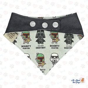 May include: A black and white dog bandana with a Star Wars theme. The bandana features a repeating pattern of Darth Vader, Boba Fett, and Stormtrooper characters. The bandana has a black adjustable strap with three white snaps.
