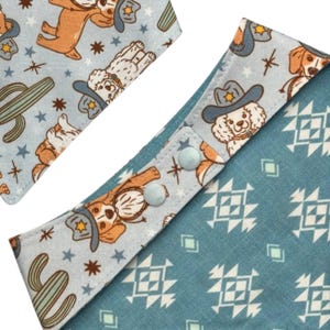 May include: Two dog bandanas with a cowboy theme. One bandana features a light blue background with cartoon dogs wearing cowboy hats, cacti, and stars. The other bandana has a teal background with white geometric patterns and light blue press studs.