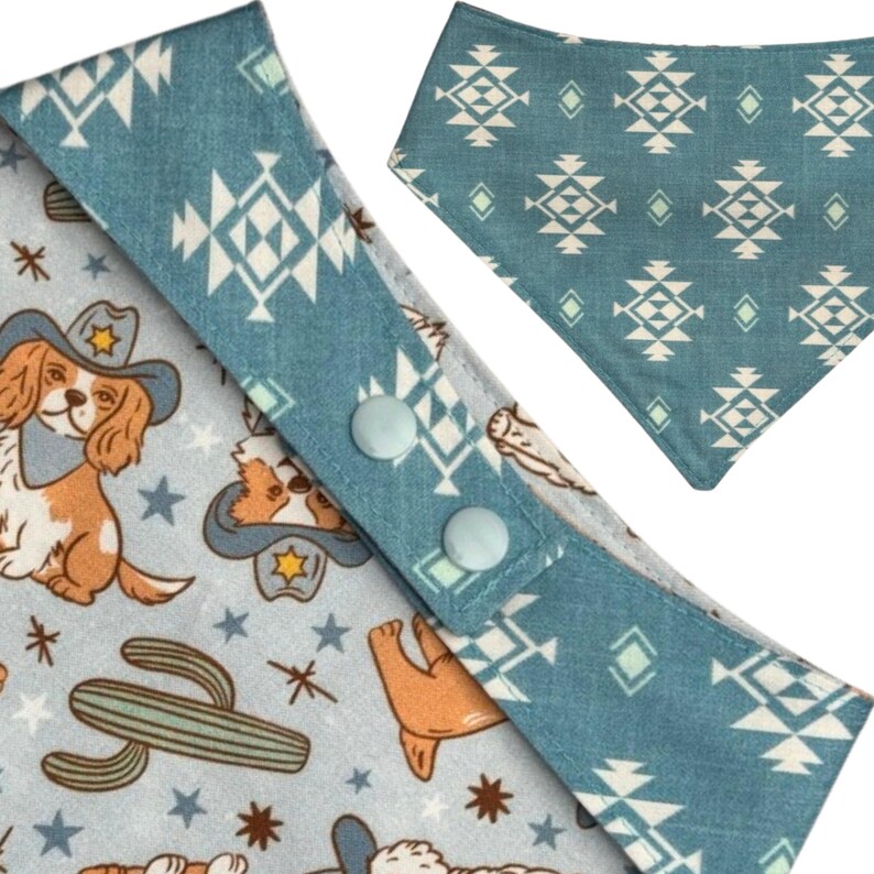 May include: Two dog bandanas. One is light blue with a repeating pattern of white geometric shapes. The other is light blue with a repeating pattern of cartoon dogs wearing cowboy hats, cacti, and stars. The bandanas have snap closures.