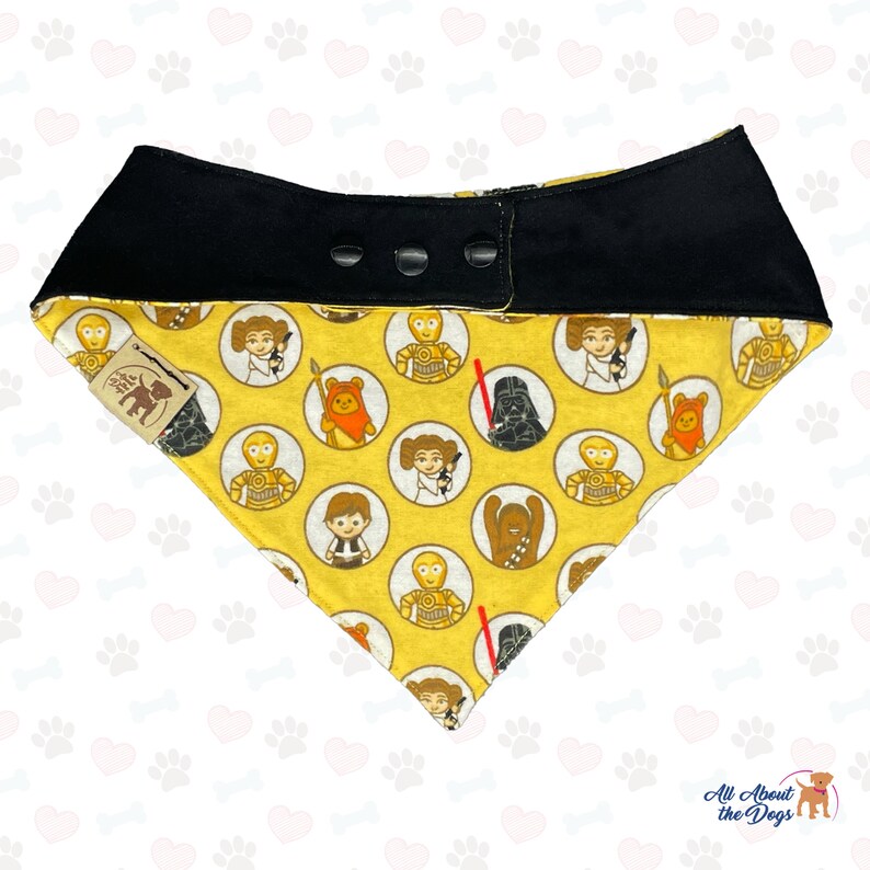 May include: Yellow dog bandana with a black adjustable collar. The bandana features a repeating pattern of Star Wars characters in circles. The characters include Darth Vader, Chewbacca, Princess Leia, R2-D2, C-3PO, and Yoda.
