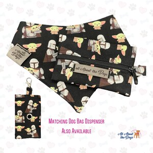 May include: A black bandana with a repeating pattern of a cartoon character, a Mandalorian, and the text "all About the Dogs". A matching black zippered pouch with the same pattern and a matching black dog poop bag dispenser with the same pattern. The text "MATCHING DOG BAG DISPENSER ALSO AVAILABLE" is printed below the image. The text "All About the Dogs" is printed in the bottom right corner of the image.