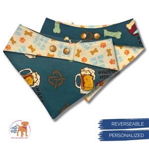 K&ouml;nnte beinhalten: Wendehalsband f&uuml;r Hunde mit teal-farbenem Hintergrund, auf dem Bierkr&uuml;ge, Brezeln und Knochen abgebildet sind. Die R&uuml;ckseite ist cremefarben mit Pfotenabdr&uuml;cken und Knochen. Das Bandana hat Druckkn&ouml;pfe.