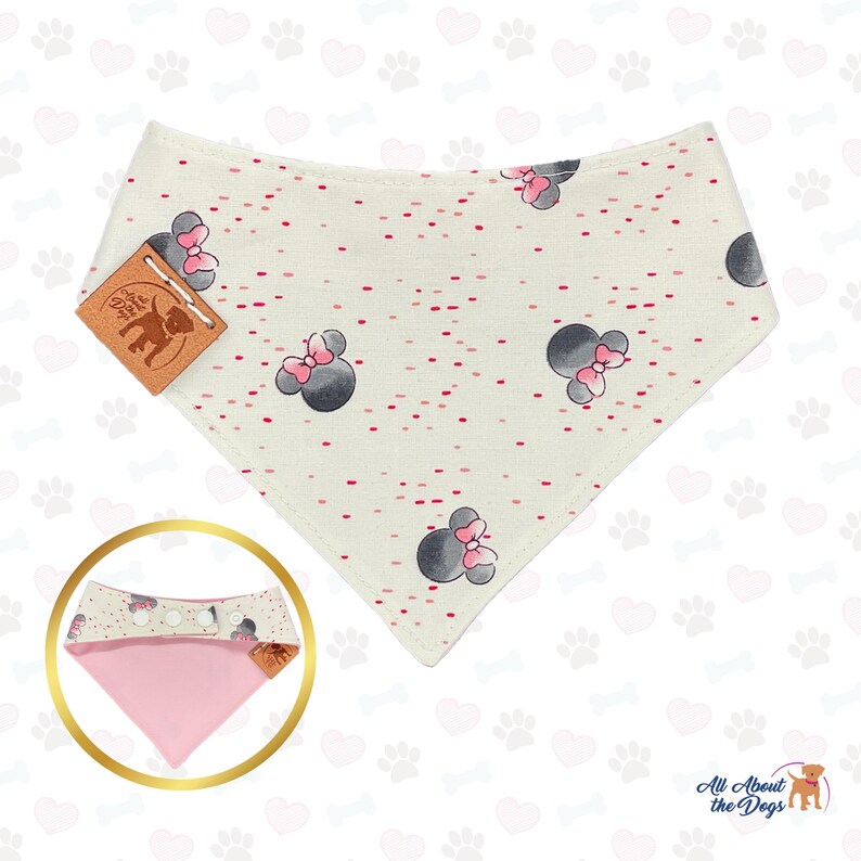 May include: Cream-colored dog bandana with a pattern of gray mouse heads with pink bows and red dots. The bandana has a pink underside and a brown leather tag. The product is for dogs.