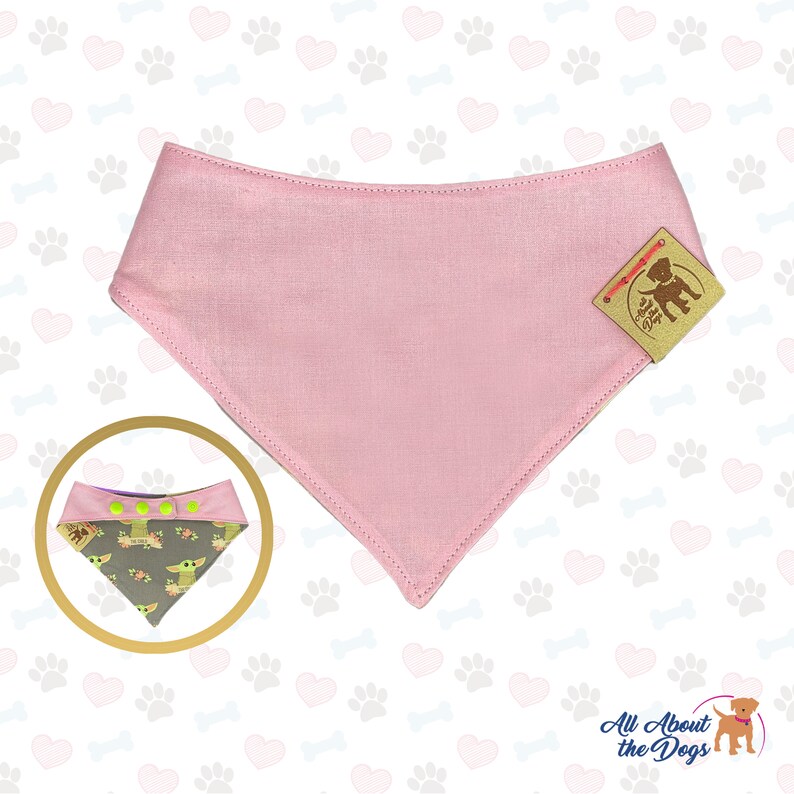 Puede incluir: Bandana rosa para perro con un patr&oacute;n verde y marr&oacute;n que presenta un personaje de dibujos animados. La bandana est&aacute; hecha de algod&oacute;n y tiene un cierre de broche. La bandana se muestra sobre un fondo blanco con un patr&oacute;n de corazones y huellas de patas.