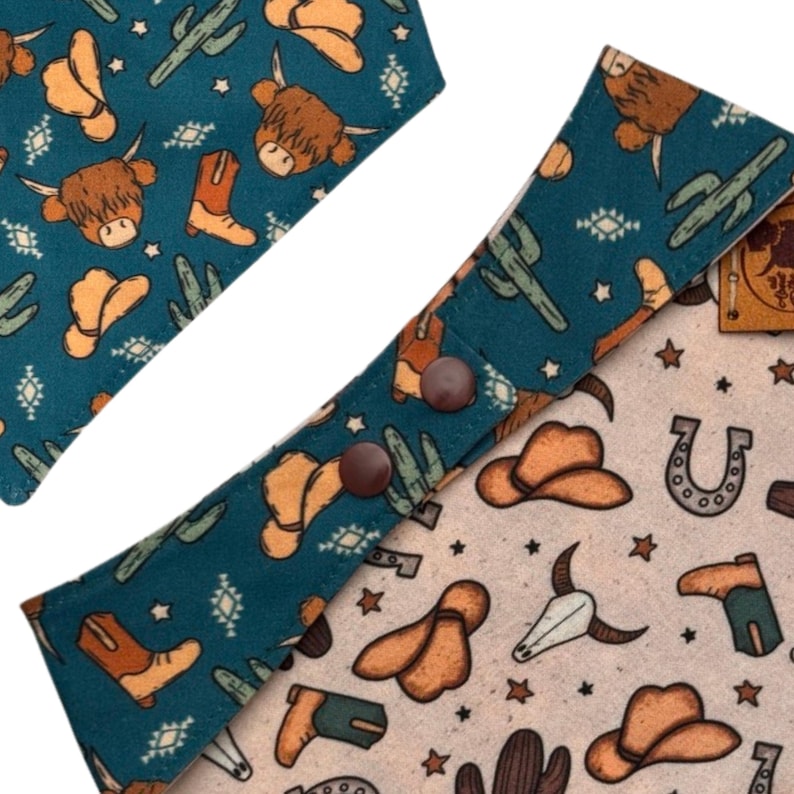 May include: Close-up of two patterned bandanas. One is teal with brown cowboy boots, hats, cacti, and Highland cows. The other is tan with cowboy hats, horseshoes, and steer skulls. The bandanas have brown snap closures.