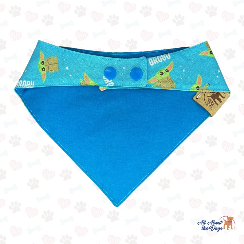 May include: A blue dog bandana with a green alien character print and the text "Grogu" on it. The bandana has two blue snap buttons and a white tag with the text "All About the Dogs".