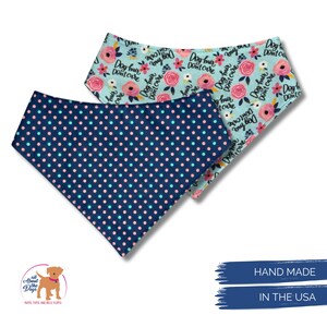 May include: Two dog bandanas. One is navy blue with pink and teal polka dots. The other is light blue with pink roses and the text "Dog hair don't care". Both are handmade in the USA.