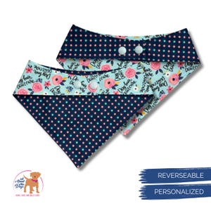May include: Two reversible dog bandanas. One side features a navy blue polka dot pattern, the other a light blue floral design with pink roses and the text "Dog hair, don't care." Each bandana has white snap closures.