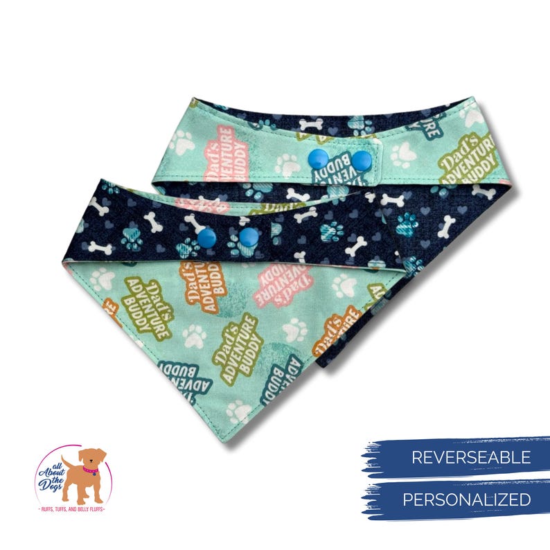 Puede incluir: Bandana reversible para perros con un estampado de huellas y huesos en azul y blanco. La bandana tiene el texto "Dad's Adventure Buddy" impreso. Es personalizada y tiene cierres a presi&oacute;n.