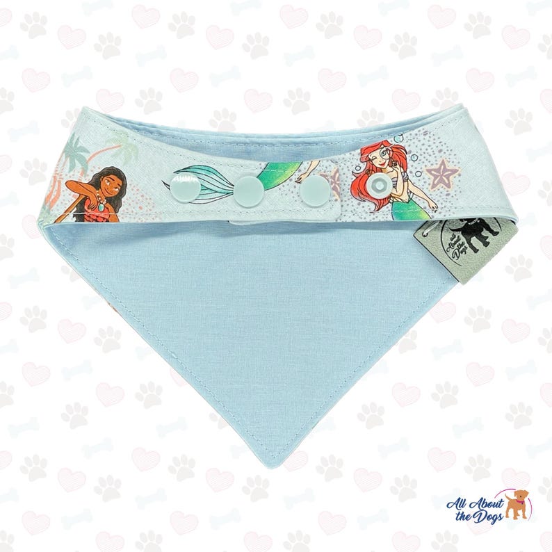 Peut inclure: Bandana bleu clair pour chien avec col blanc orn&eacute; de personnages de dessins anim&eacute;s. Le col comporte trois boutons vert clair et une &eacute;tiquette avec une silhouette de chien noir. Le bandana est de forme triangulaire.