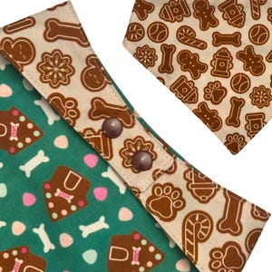 K&ouml;nnte beinhalten: Zwei Hunde-Bandanas mit festlichem Lebkuchen-Thema. Eines ist gr&uuml;n mit Knochen- und Lebkuchenhaus-Designs, das andere ist beige mit Lebkuchenm&auml;nnern, Knochen und Pfotenabdr&uuml;cken. Beide haben braune Druckkn&ouml;pfe.