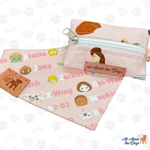 May include: A pink dog bandana and matching zippered pouch featuring Star Wars characters and text. The bandana and pouch have a repeating pattern of paw prints. The bandana has a leather tag that says "All About the Dogs".