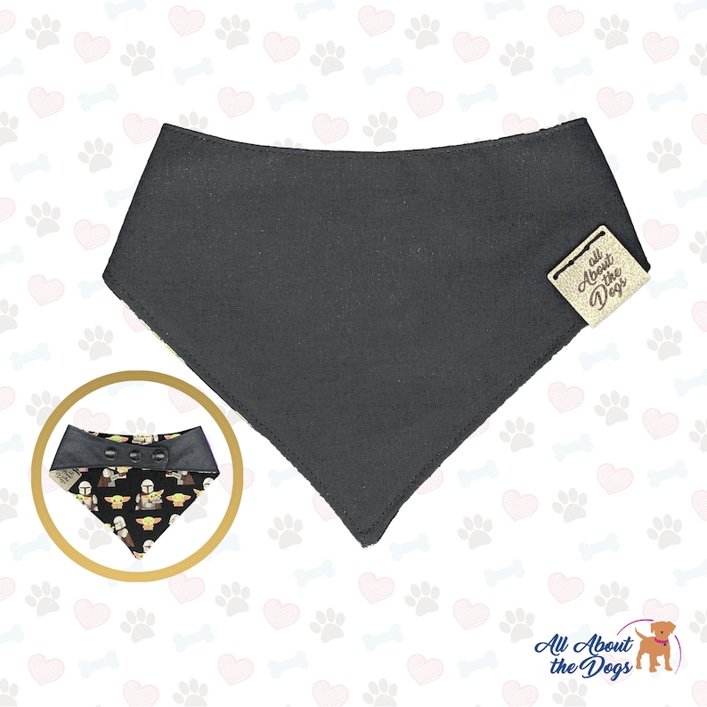 May include: A black dog bandana with a reversible side featuring a pattern of cartoon baby Yoda characters. The bandana has a snap closure and a brown leather tag that says "All About the Dogs".