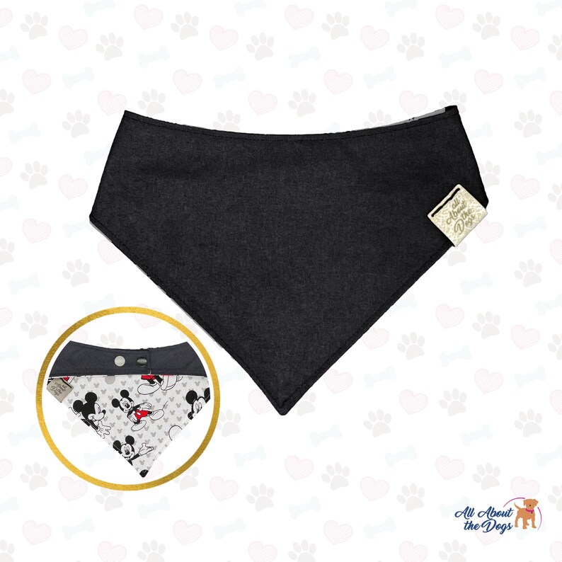 May include: A black dog bandana with a contrasting Mickey Mouse print. The bandana has a snap closure and a tag that reads "All About the Dogs". The bandana is a triangle shape.