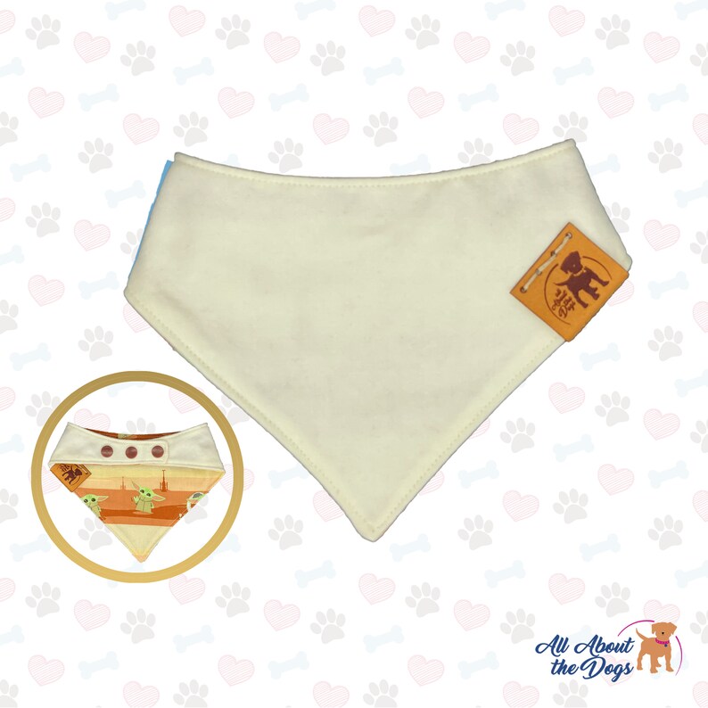 May include: Cream-colored dog bandana with a brown leather tag. A smaller, circular image shows a patterned bandana with a Baby Yoda design. The background is white with paw prints and hearts. The bandana is a pet accessory.
