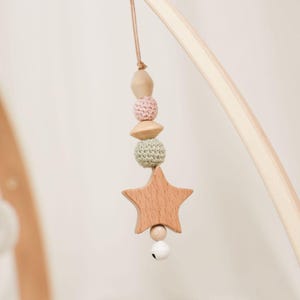 Pode incluir: M&oacute;vel de beb&eacute; em madeira com um pendente em forma de estrela, contas de croch&eacute; e madeira em cores pastel e um pequeno sino. O m&oacute;vel &eacute; suspenso de um arco de madeira. Uma decora&ccedil;&atilde;o encantadora para o quarto do beb&eacute;.