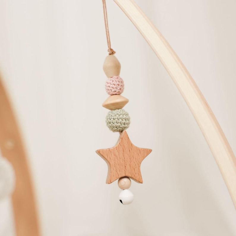 Pode incluir: M&oacute;vel de beb&eacute; em madeira com um pendente em forma de estrela, contas de croch&eacute; e madeira em cores pastel e um pequeno sino. O m&oacute;vel &eacute; suspenso de um arco de madeira. Uma decora&ccedil;&atilde;o encantadora para o quarto do beb&eacute;.