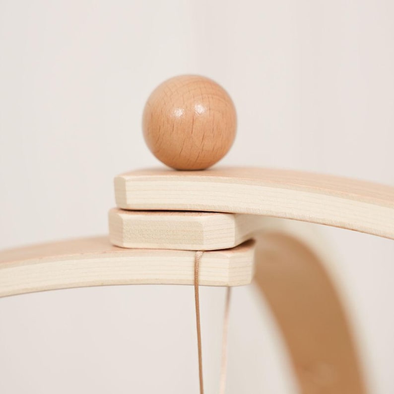 Pode incluir: M&oacute;vel de madeira com acabamento natural. Apresenta uma pequena bola de madeira redonda equilibrada sobre uma estrutura de madeira curva. Uma fina corda pende da parte inferior, adicionando ao design delicado do m&oacute;vel.