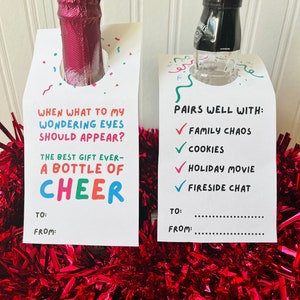 May include: Two bottle tags with festive text and colorful confetti. One tag reads "When what to my wondering eyes should appear? The best gift ever - a bottle of cheer." The other says "Pairs well with: Family Chaos, Cookies, Holiday Movie, Fireside Chat."