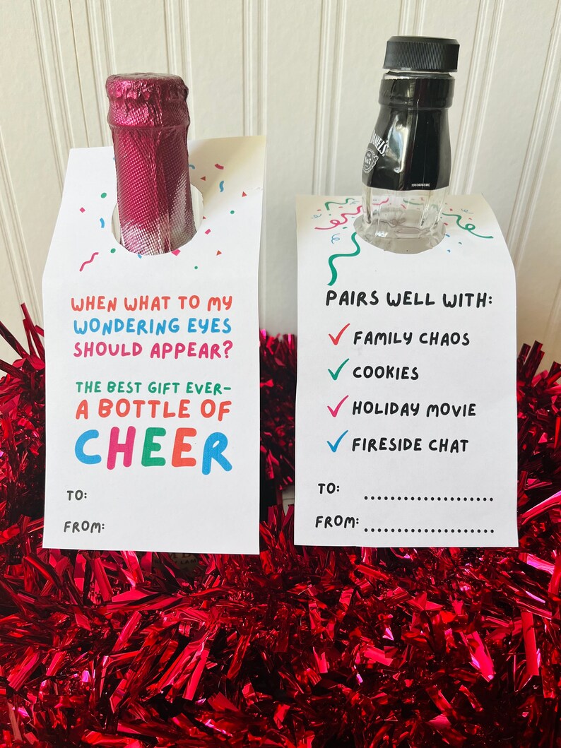 May include: Two bottle tags with festive text and colorful confetti. One tag reads "When what to my wondering eyes should appear? The best gift ever - a bottle of cheer." The other says "Pairs well with: Family Chaos, Cookies, Holiday Movie, Fireside Chat."