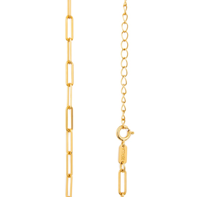 May include: A gold-coloured necklace featuring a paperclip chain design. The necklace has an elongated link pattern. The clasp and extender chain are visible. The brand name "DECALLA" is engraved on the clasp.