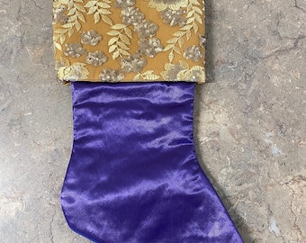 Media navideña con cordones de satén morado y dorado.