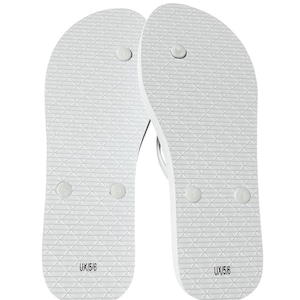 May include: A pair of white flip-flops featuring a textured diamond pattern on the footbed. Each sandal displays the text UX/5/6 printed in black near the heel area, along with three circular plug points for the toe post and strap attachments.