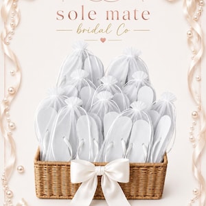 May include: A rectangular woven wicker basket containing multiple pairs of white flip-flops, each individually packaged in a sheer white organza drawstring bag. A large white satin ribbon bow is attached to the front of the basket.