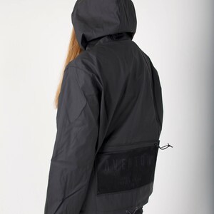 May include: Black hooded jacket with a mesh pocket on the back featuring the text "AVE ANTONY" in white.