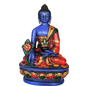 Könnte beinhalten: Blaue bemalte Buddha-Statue, die im Meditations-Sitz mit einem roten und goldenen Gewand sitzt. Die Statue steht auf einem blauen Sockel mit goldenen und roten Akzenten.