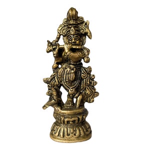 Könnte beinhalten: Eine goldfarbene Metallstatue von Krishna, der Flöte spielt, steht auf einem Sockel mit aufwendigen Details. Die Statue ist eine traditionelle hinduistische Gottheit.