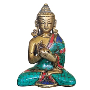 Puede incluir: Una pequeña estatua dorada de Buda sentado en posición de meditación. La estatua está decorada con piedras turquesa y rojas.