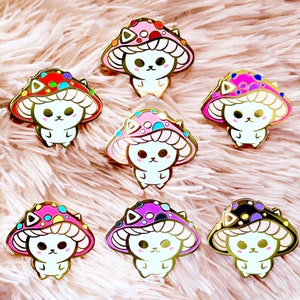 Pode incluir: Conjunto de sete pinos de esmalte dourado com gatos de desenho animado usando chapéus de cogumelo. Cada chapéu de cogumelo tem uma cor e um padrão diferente.