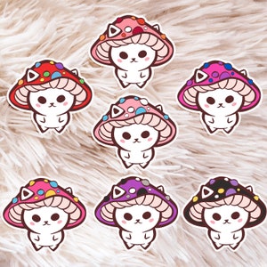 May include: Seven colorful mushroom stickers with cute white cats wearing mushroom caps. Each sticker features a different color combination of pink, purple, red, blue, yellow, and black.