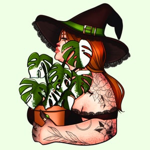 May include: A woman with red hair wearing a black witch hat with a green band holds a potted monstera plant. She has tattoos on her arms and shoulders.