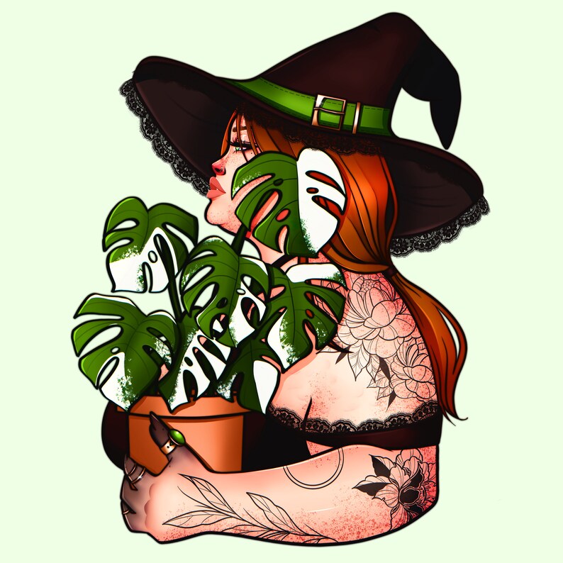May include: A woman with red hair wearing a black witch hat with a green band holds a potted monstera plant. She has tattoos on her arms and shoulders.
