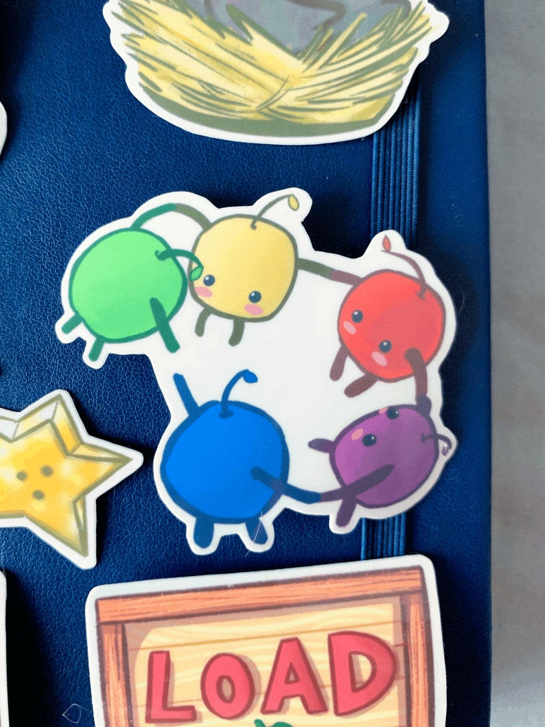 May include: Five colourful cartoon characters holding hands in a circle. The characters are green, yellow, red, blue, and purple. The characters are on a white background.