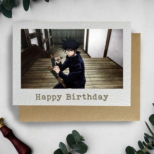 May include: A birthday card featuring an anime character holding two wooden sticks in a fighting stance. The card has a brown background and the text "Happy Birthday" in white.