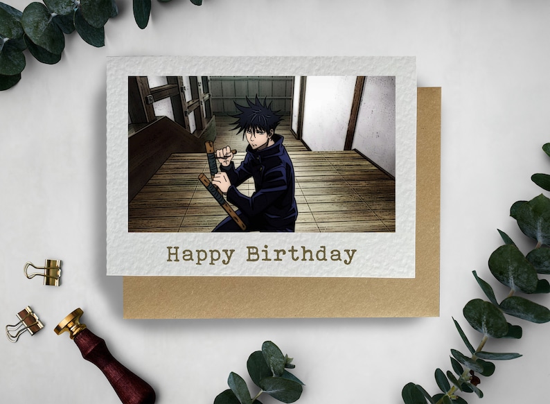 May include: A birthday card featuring an anime character holding two wooden sticks in a fighting stance. The card has a brown background and the text "Happy Birthday" in white.