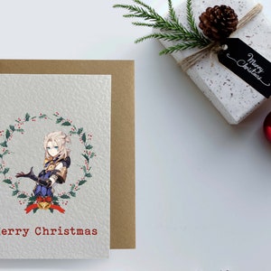 May include: A Christmas card featuring an anime-style character with blonde hair standing in a wreath of holly. The card has the text "Merry Christmas" in red.