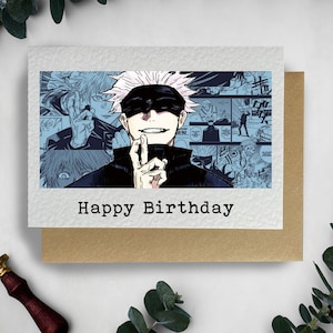 May include: A birthday card featuring a black and white illustration of a character from a manga series. The character has white hair and is wearing a black shirt and a blindfold. The card has the text "Happy Birthday" printed on it.